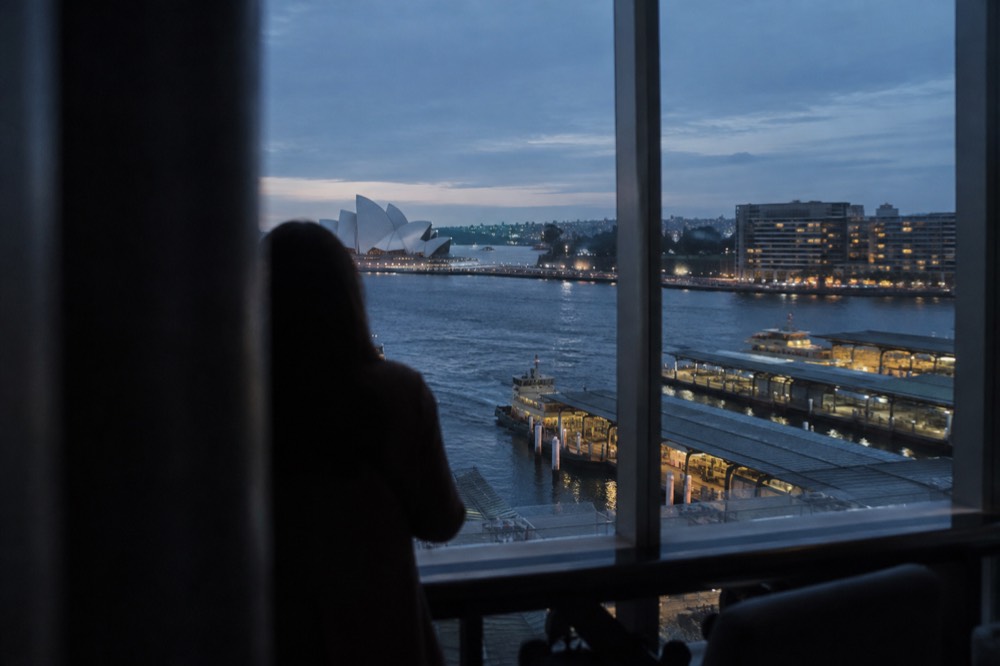 City observation deck interior with floor-to-ceiling windows over the harbour at dusk
