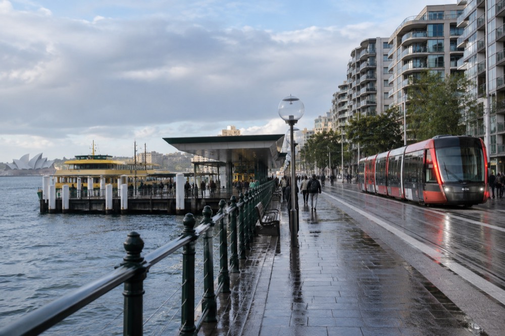 A tram passing modern apartment buildings on a Sydney street