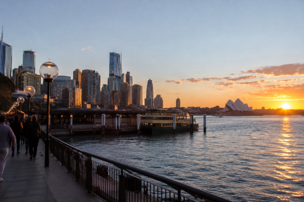 Evening light installations glowing along the harbour foreshore with the city skyline behind