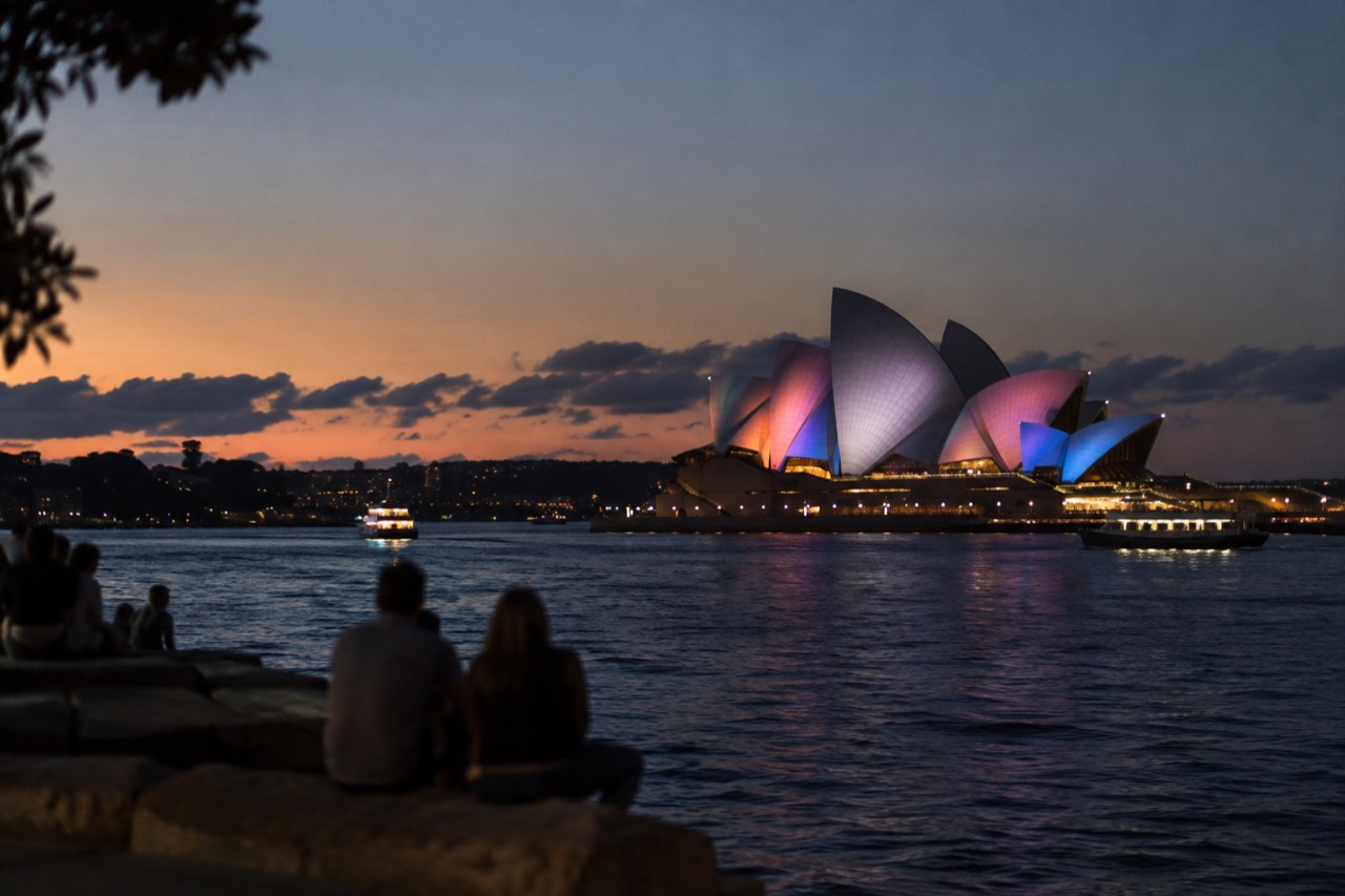 Sydney Opera House sails lit with colourful festival lighting above a dark harbour
