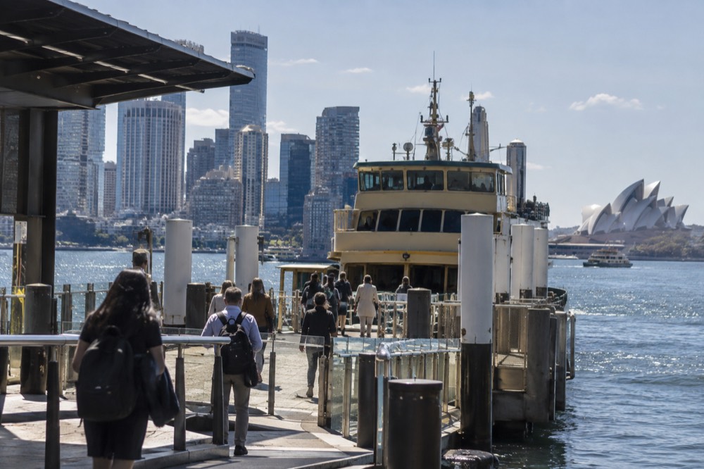 Ferry gangway gates at Circular Quay with the city skyline behind the wharves