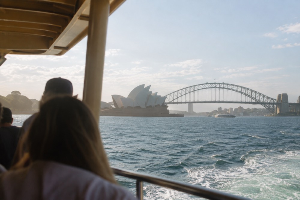 A cruise boat passing the Sydney Opera House on a clear afternoon