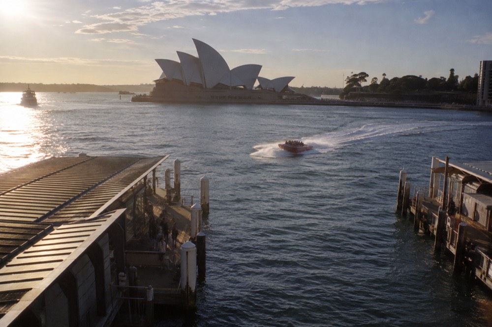 A jet boat cutting a tight turn on Sydney Harbour with the Opera House in the background