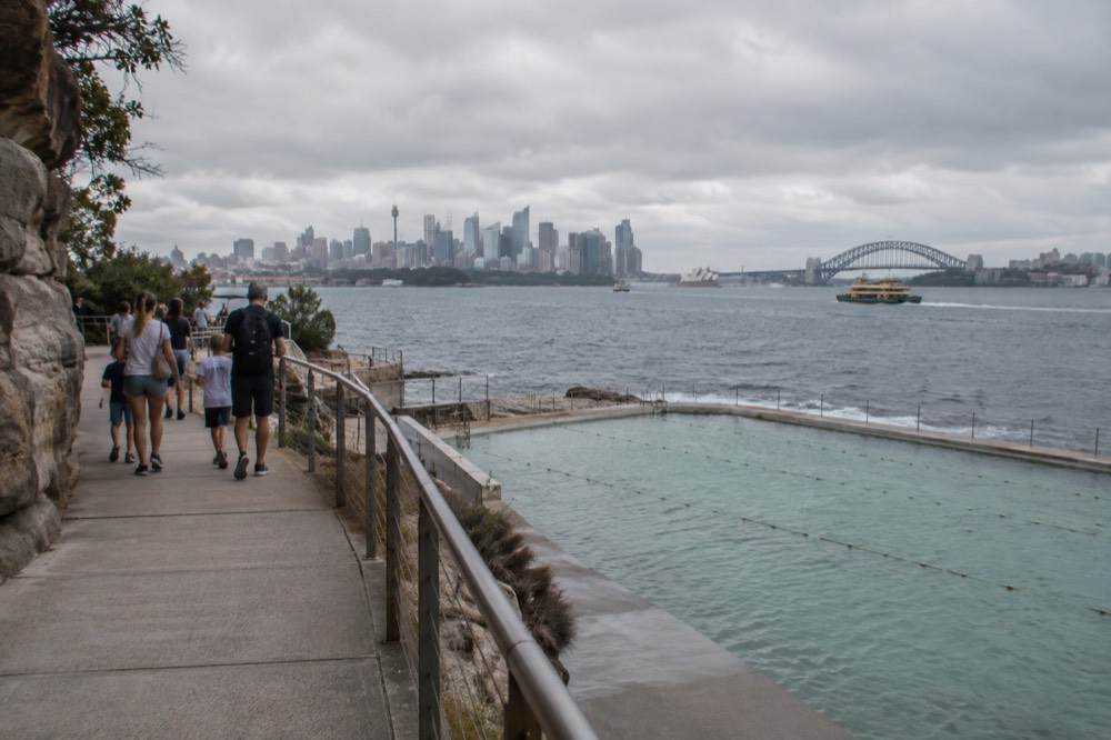 Family groups walking a coastal path above an ocean pool