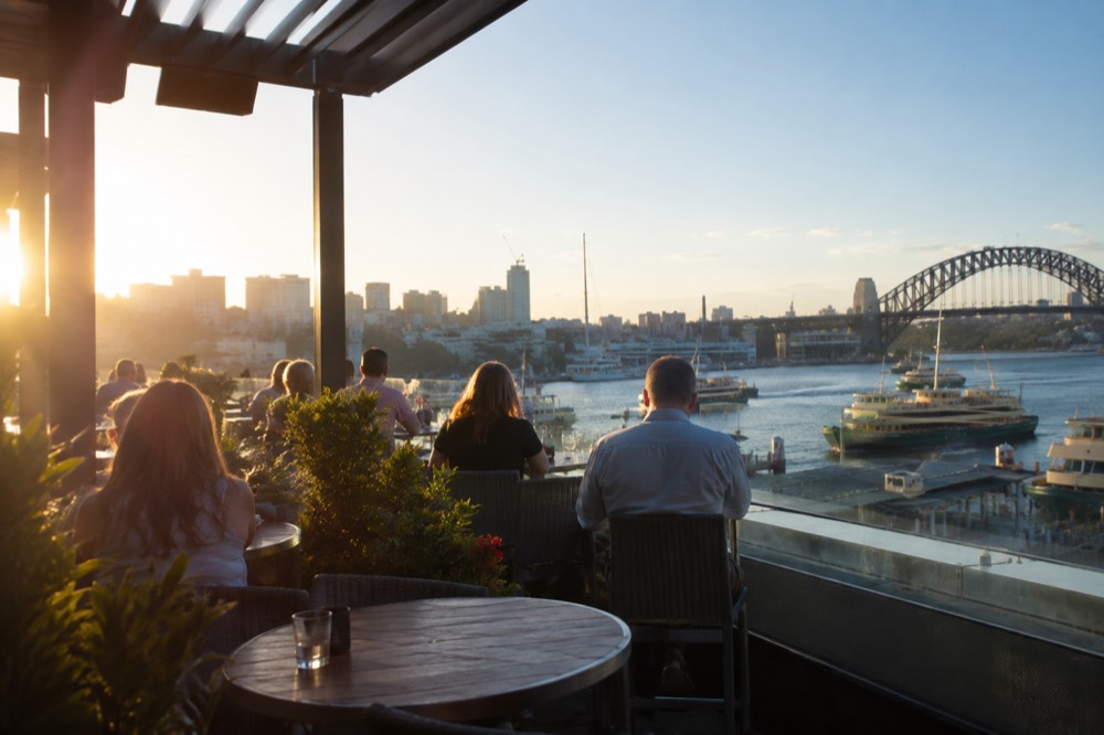 Open-air rooftop terrace under a clear sky above the Sydney skyline