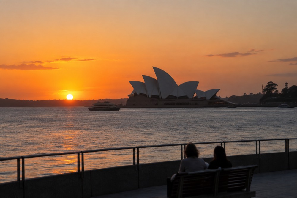 Golden sunrise light over Sydney Harbour with the Opera House silhouetted against an orange sky