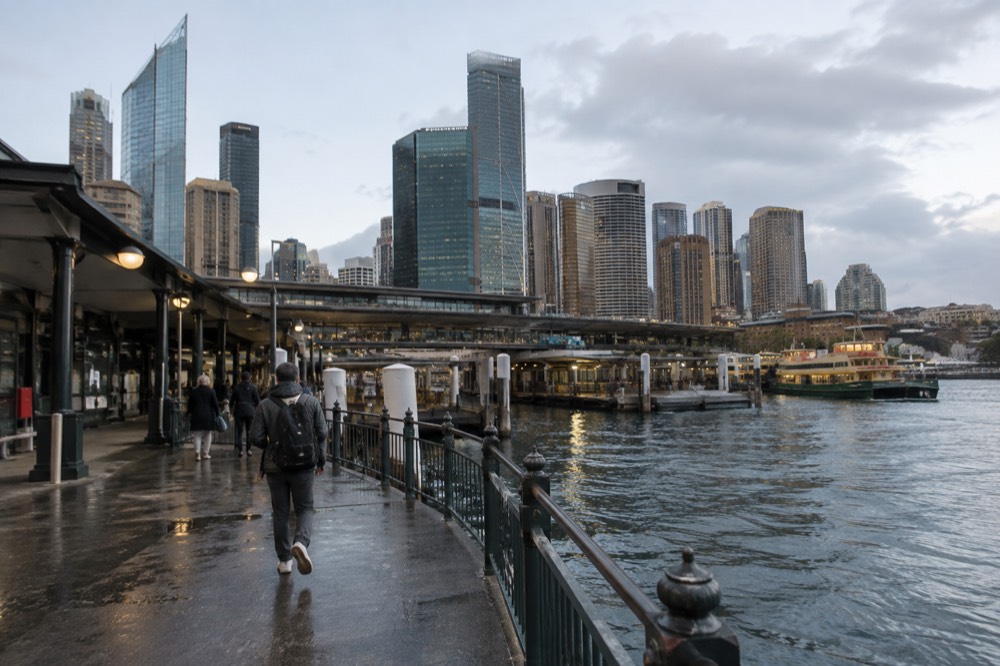 A ferry terminal beside a train station at the edge of the CBD with harbour water in the foreground