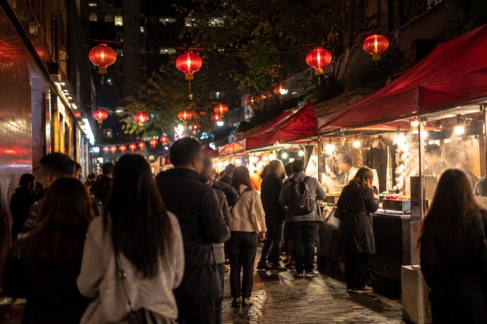 Chinatown food stalls glowing under red lanterns at night with crowds queuing