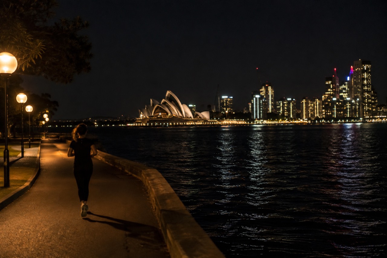 Sydney Harbour at night with the Opera House and city skyline lit up over dark water
