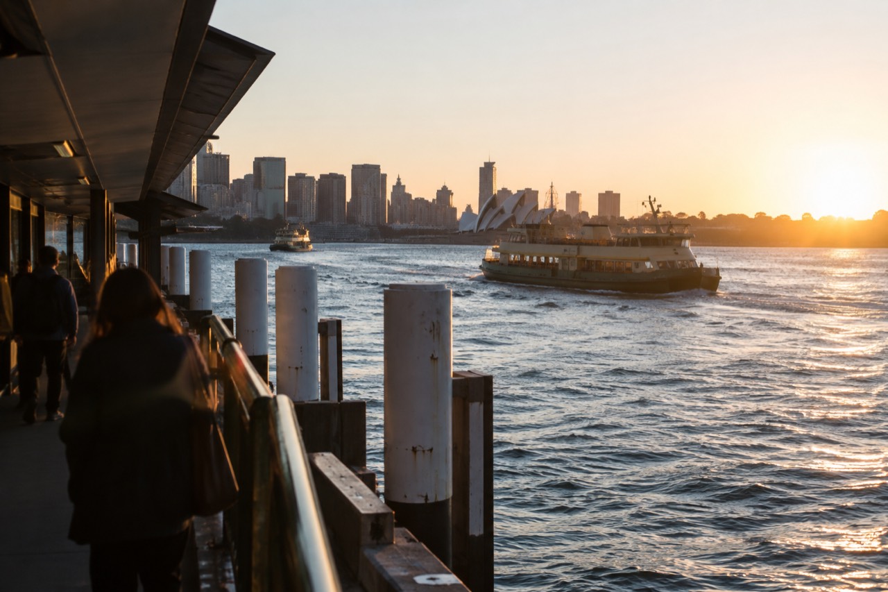 Sydney skyline seen across the water at dusk with ferries on the harbour