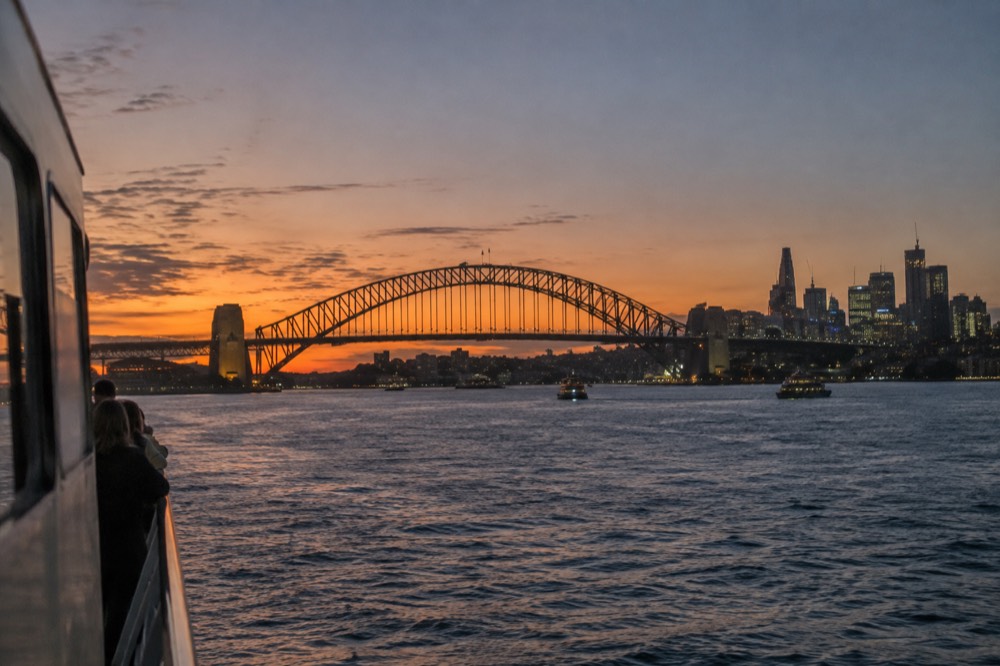 Sunset light on Sydney Harbour Bridge and the city skyline from the water