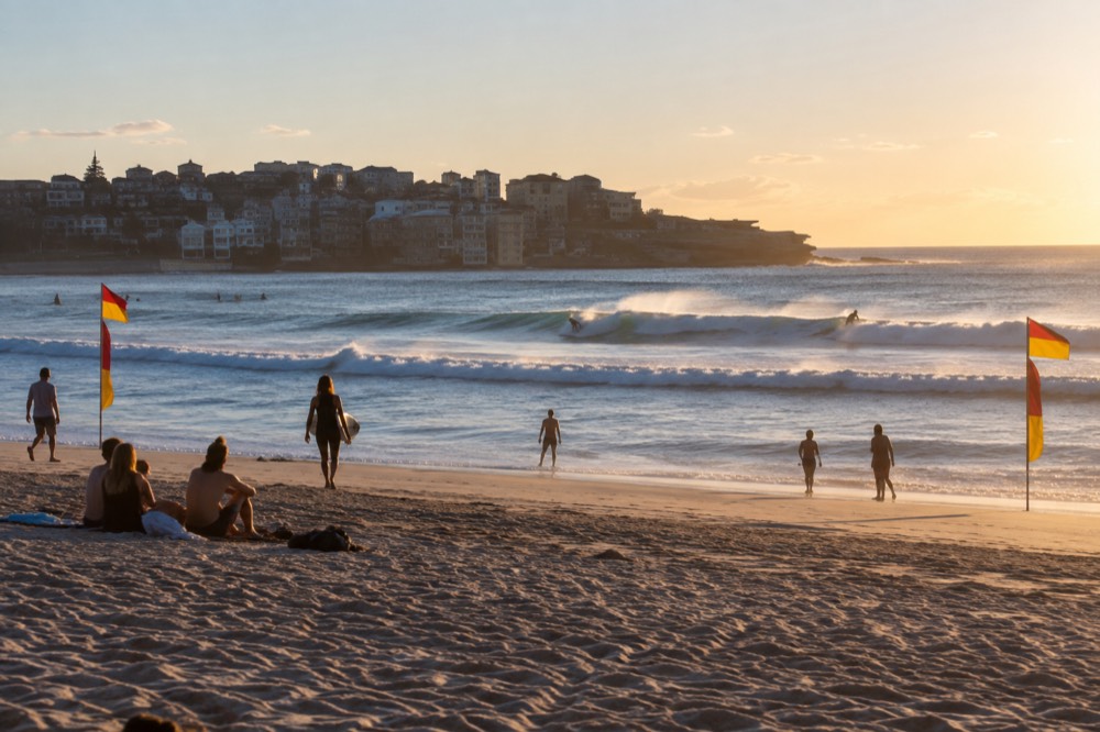 Waves breaking at Bondi Beach with the red and yellow patrol flags visible on the sand