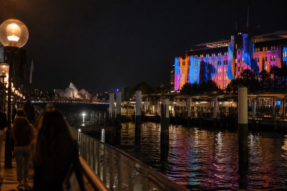 Colourful light projections washing over a harbour-side building at night