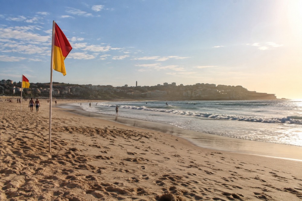 Red and yellow patrol flags on a wide sandy beach in the morning
