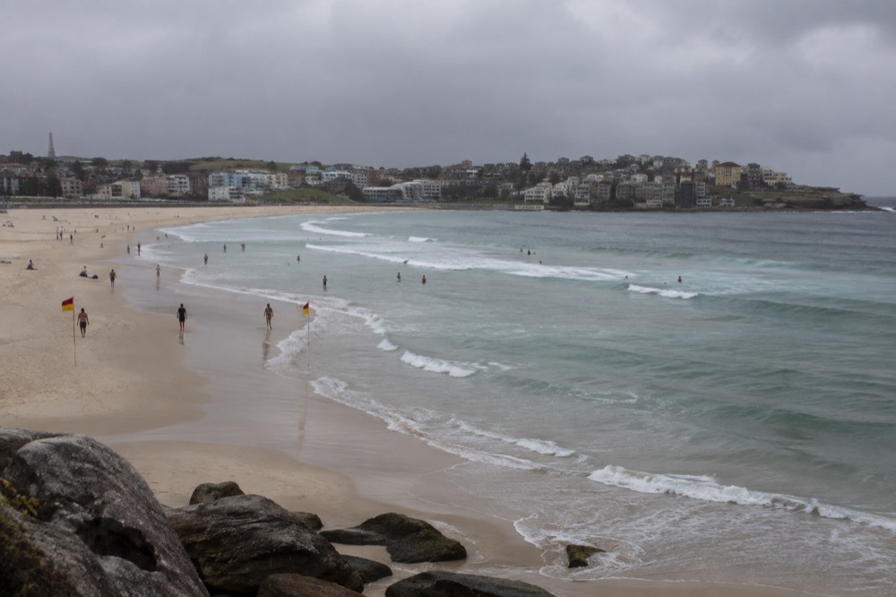 Bondi Beach at mid-morning with lifeguard flags and gentle surf