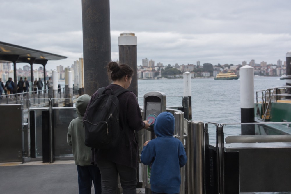 Opal card reader at a ferry wharf gate with a family tapping on